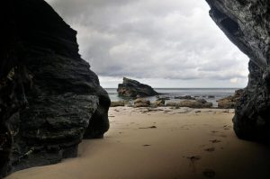 Explore the stunning rocky beach landscape visible from a coastal cave in Camborne, England.