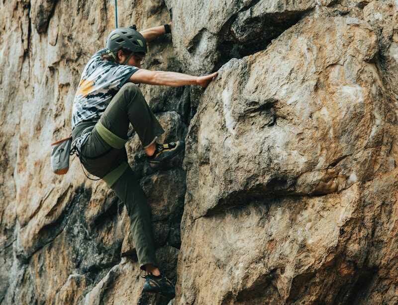 man in black t-shirt climbing on brown rock during daytime