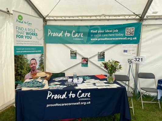 Proud to Care Cornwall stand showing a table and banners in a marquee