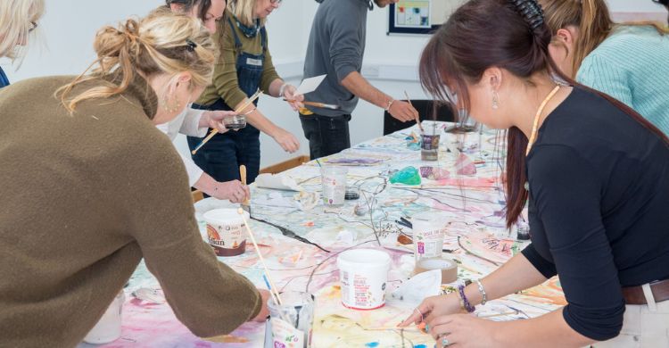 Photograph shows people painting around a table