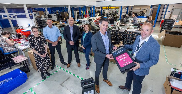 Photograph shows a group of six people stood inside a warehouse