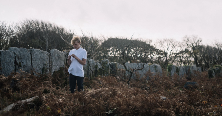 A boy next to a stone wall