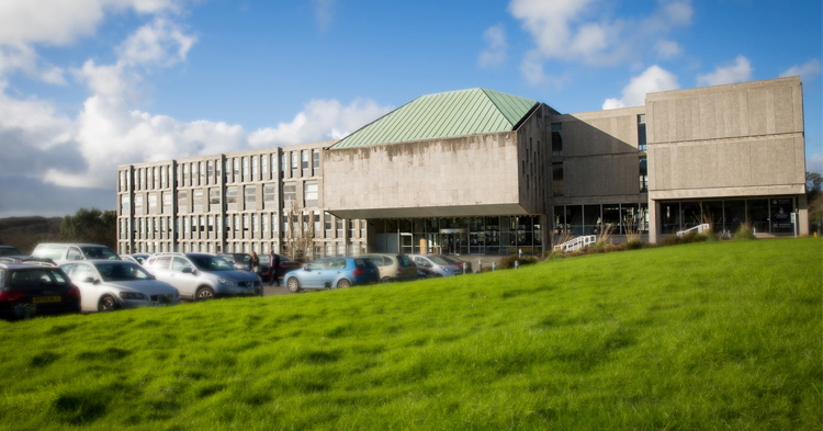 Photograph of County Hall in Truro, a grey rectangular building with a car park and grassy area in front of it