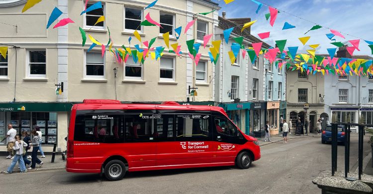 Image shows an electric bus driving through a shopping area