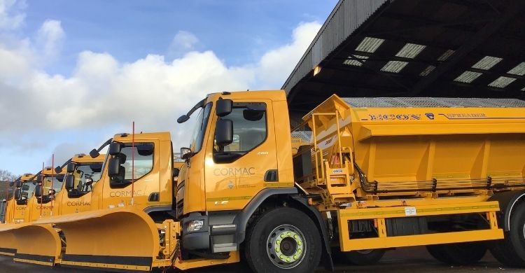 Five yellow gritters in a line