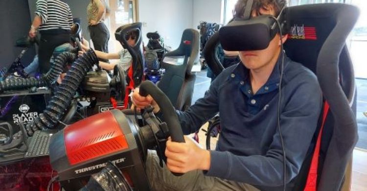 Person wearing a VR headset sitting in gaming chair holding a steering wheel