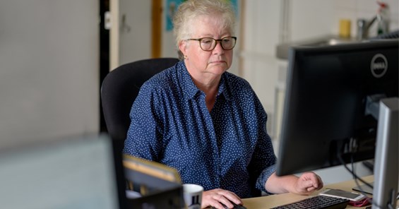 An older woman sat at her desk looking at her computer