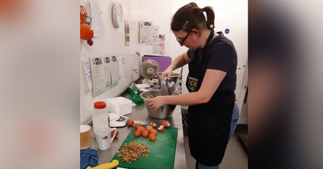 Abi is using a mixer in a kitchen