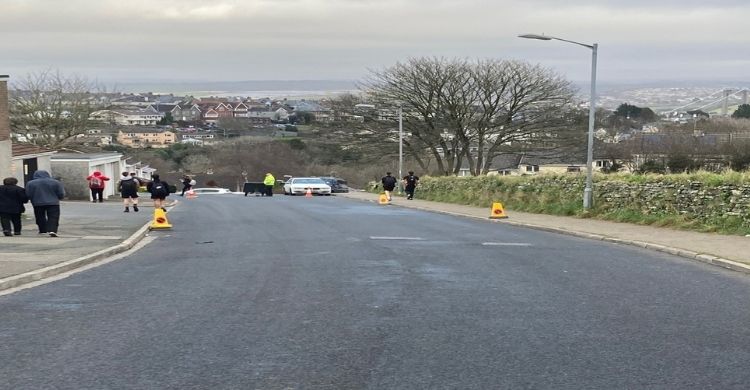 Photograph of a road with people walking on pavements either side of the road