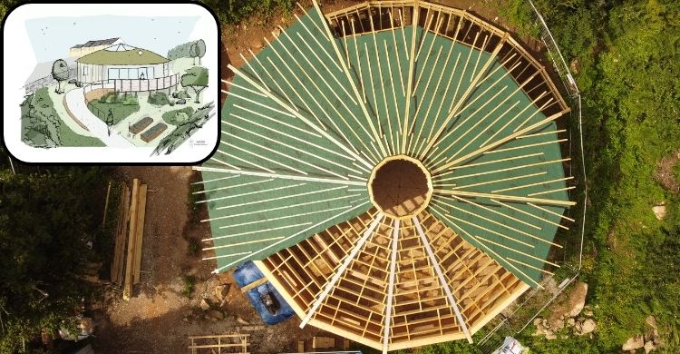 Image shows an aerial view of a circular building under construction. There is a picture of an artist's impression of a building embedded within the main image