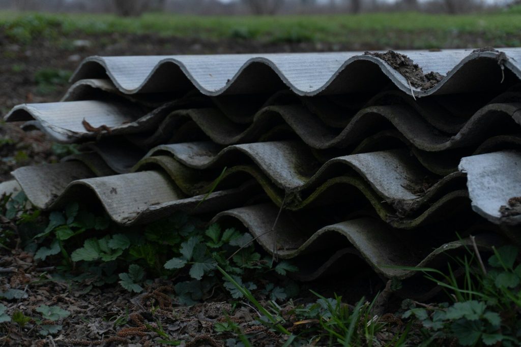 Stack of weathered corrugated asbestos cement sheets