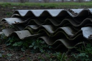 Stack of weathered corrugated asbestos cement sheets